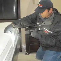 Bed bug inspection technician checking a mattress and bed frame for signs of infestation in Naperville, IL