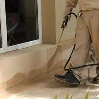 General pest control technician spraying exterior perimeter around a home in Naperville, IL