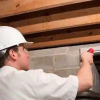 Termite inspection technician checking a basement wall and framing for termite activity in Naperville, IL
